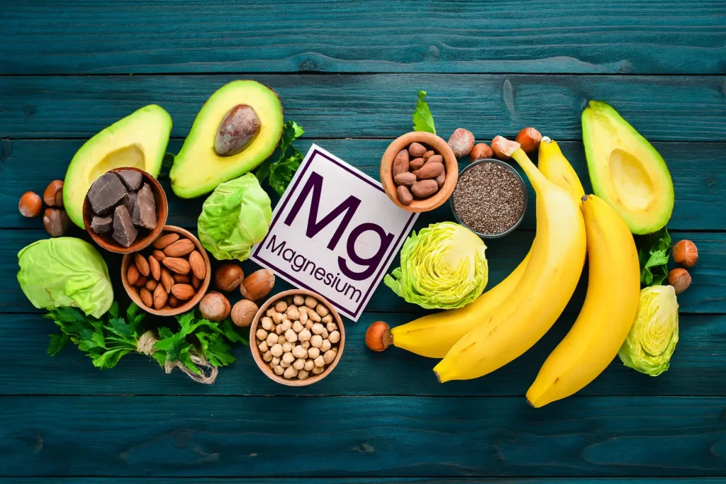 Magnesium rijke voeding zoals avocado, bananen, noten, zaden en groenten op houten achtergrond met Mg-symbool in het midden